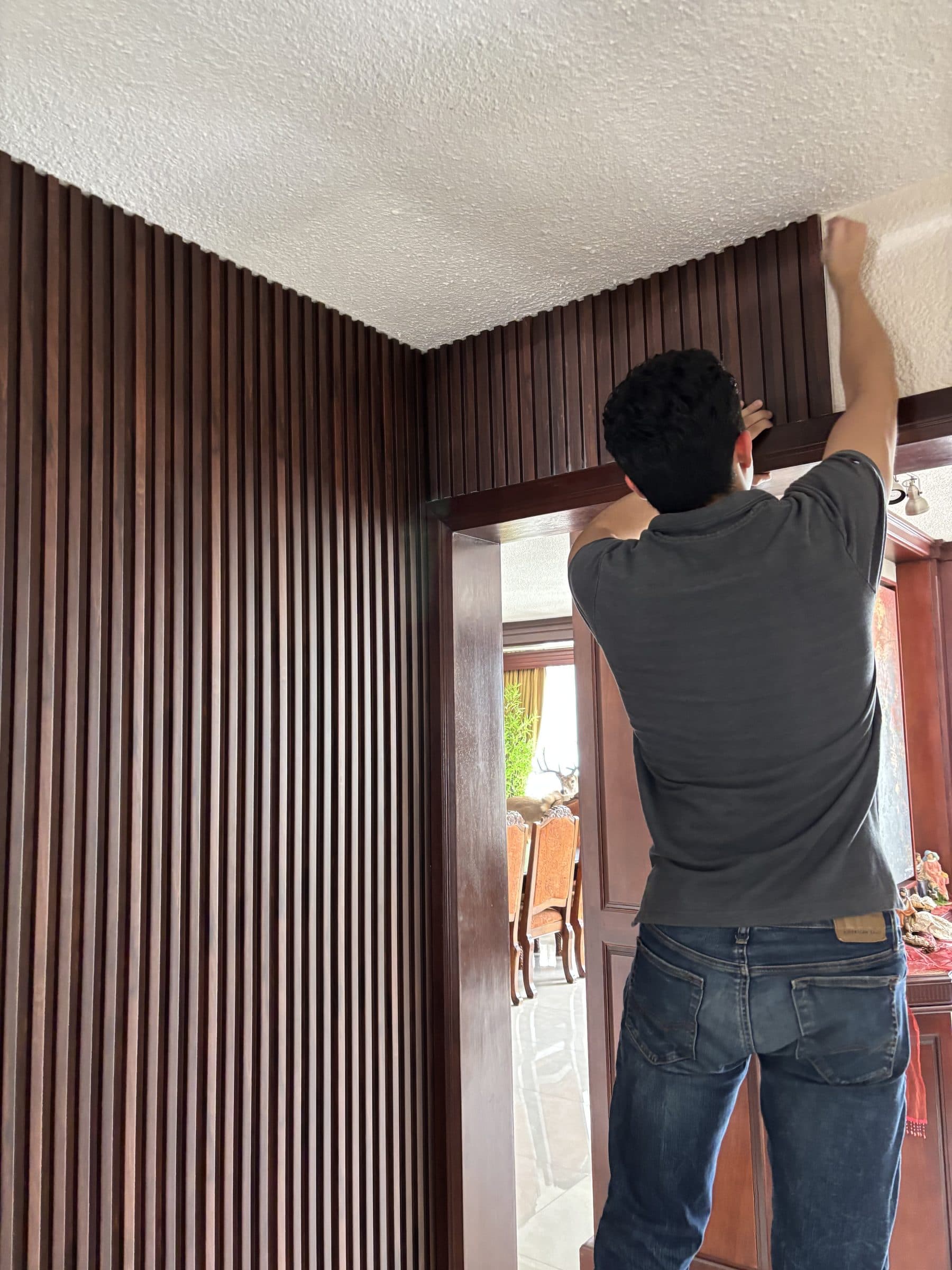 Instalador Decktek colocando lambrín WPC oscuro en muro residencial