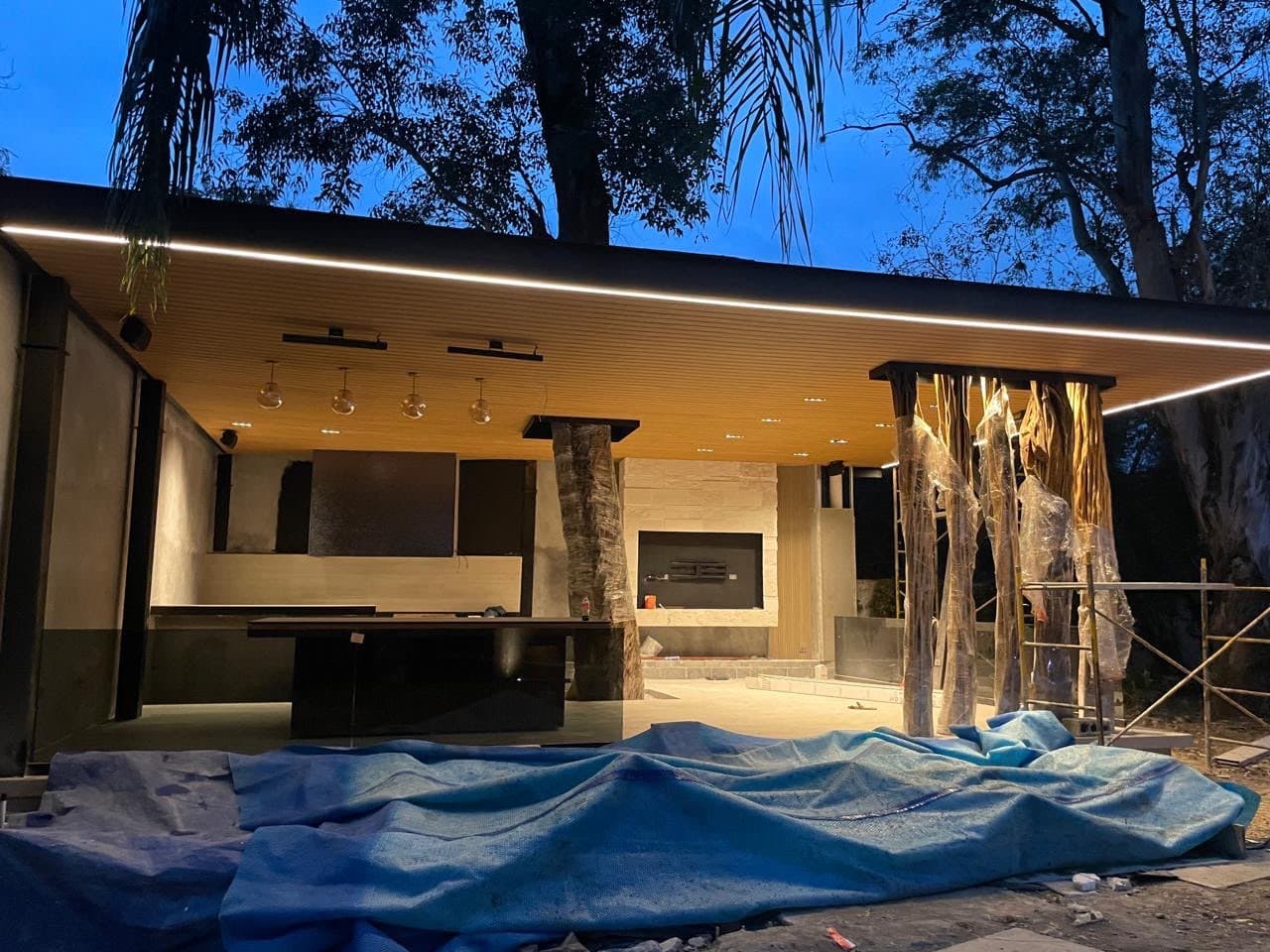 Terraza residencial de noche con plafón de listones WPC iluminado con luz lineal cálida